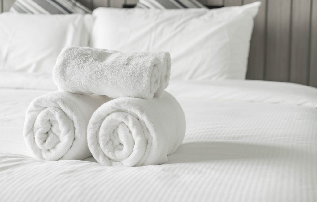 white towels stacked on top of each other on top of a white bed