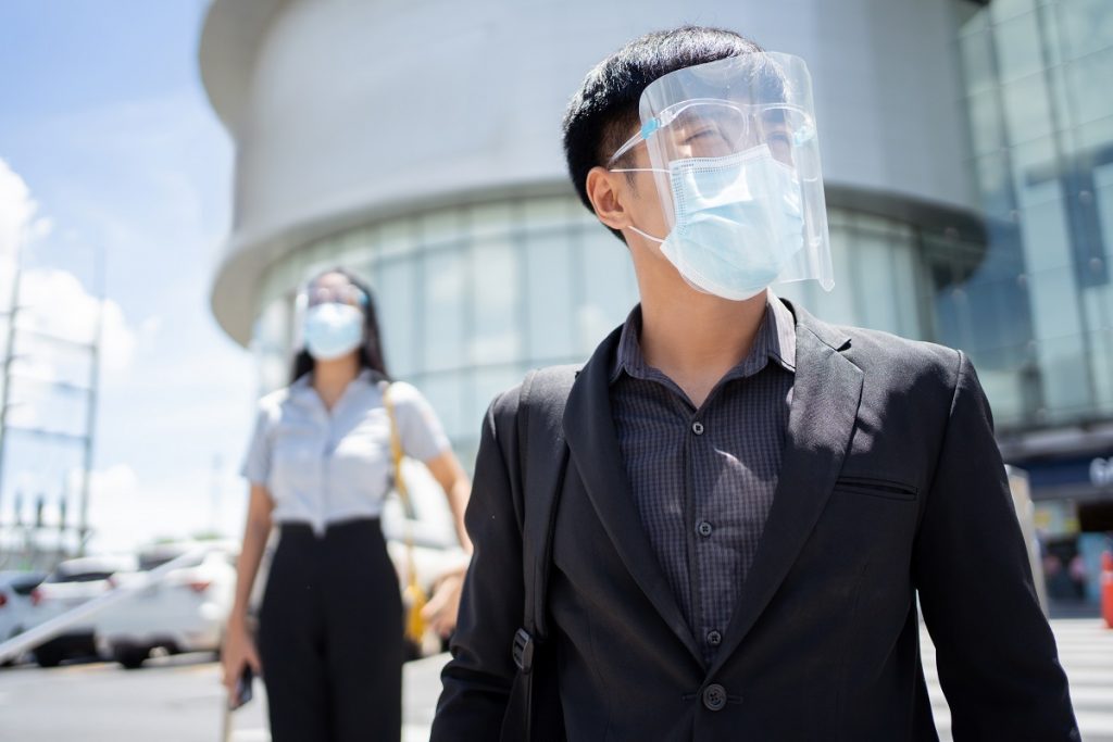 Asian working man, wearing a mass and face shield, protect the virus