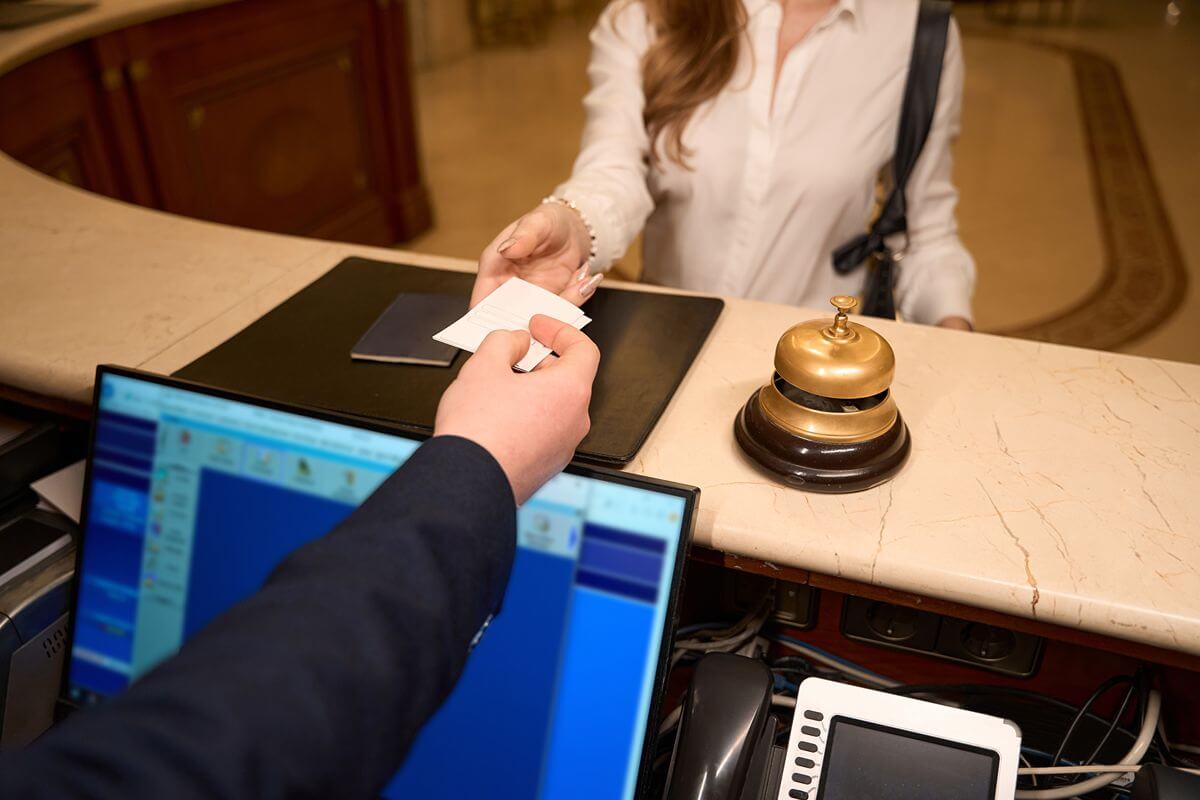 Hotel guest presenting a card at the front desk while staff manage attendance and access records